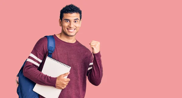 Joven Joven Guapo Hispano Con Mochila Estudiantil Cuaderno Gritando Orgulloso —  Fotos de Stock