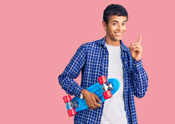 Young African Amercian Man Holding Skate Surprised Idea Question Pointing — Stock Photo, Image