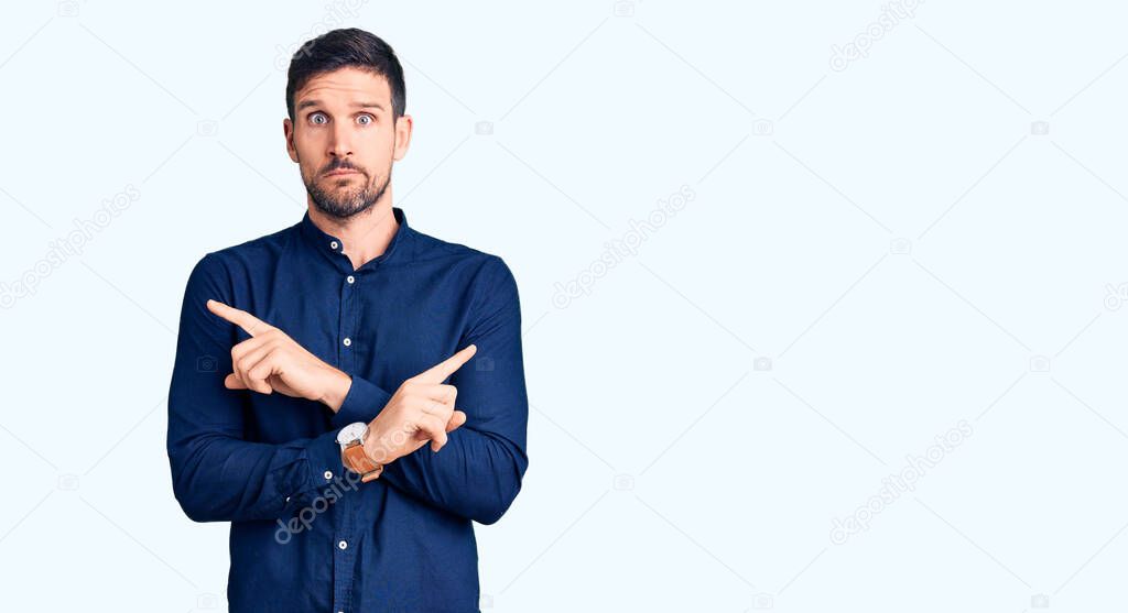 Young handsome man wearing casual shirt pointing to both sides with fingers, different direction disagree 