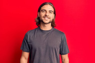 Yüzünde mutlu ve havalı bir gülümseme olan sıradan kıyafetler giyen genç yakışıklı bir adam. şanslı kişi. 