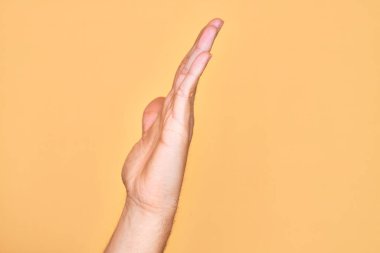 Kafkasyalı bir gencin eli, sarı arka planda parmaklarını gösteriyor. Uzanmış el hareketlerini gösteriyor, itiyor ve duruyor.