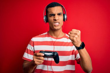 Yakışıklı afro-amerikan oyuncu video oyunu oynuyor jostick ve kulaklık kullanıyor sinirlenmiş ve hayal kırıklığına uğramış öfkeyle bağırıyor ve el kaldırarak bağırıyor.