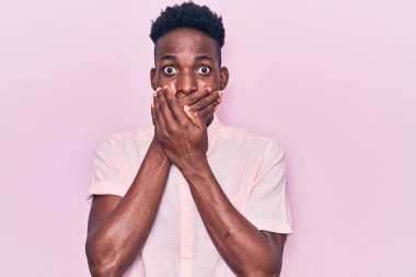 Gündelik giysiler giyen genç Afro-Amerikan bir adam yanlışlıkla elleri ile ağzını kapatırken şok oldu. gizli kavram. 