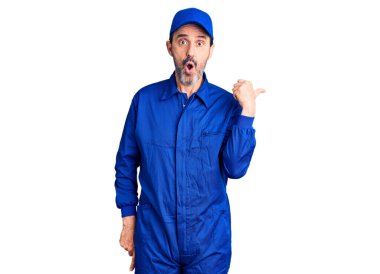 Tamirci üniforması giyen orta yaşlı yakışıklı bir adam elleri yana doğru işaret ederek şaşırdı, ağzı açık hayret içinde kaldı.. 