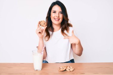 Genç, güzel, esmer bir kadın. Bir bardak taze süt içiyor. Kurabiyeli. 