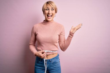 Kısa saçlı, kısa saçlı genç bir kadın. Ölçüm bandı kullanıyor. Çok mutlu ve heyecanlı.