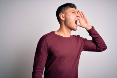 Beyaz izole edilmiş arka planda durup el ele tutuşarak bağıran genç, yakışıklı İspanyol gömlekli bir adam. İletişim konsepti.