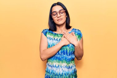 Genç, güzel Latin bir kadın, sıradan kıyafetler giyiyor, elleri göğsünde gülümsüyor, gözleri kapalı, yüzünde minnet ifadesi var. sağlık kavramı. 