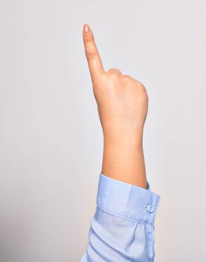 Beyaz arka plan üzerinde gerilmiş işaret parmağıyla yumruk sembolü çizen beyaz bir kadının eli.