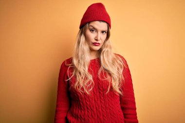 Genç, güzel, sarışın bir kadın beyaz arka plan kuşkucu ve gergin üzerine yün başlık giyip sorun yüzünden surat asıyor. Negatif kişi.