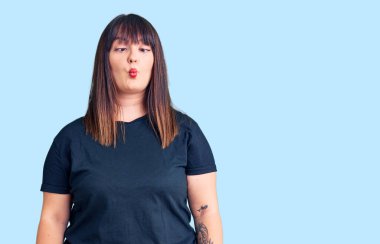 Genç ve cüsseli bir kadın günlük kıyafetler giyiyor, dudaklarıyla balık suratı yapıyor, çılgınca ve komik hareketler yapıyor. Komik ifade. 