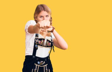 Sarışın, güzel bir kadın. Ekim festivali kıyafeti giyiyor. Yumruk yumruğa dövüşüyor. 