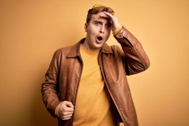 İzole edilmiş sarı arka plan üzerine sıradan deri ceket giyen genç, kızıl saçlı bir adam. Hatayla el ele tutuşurken şaşırmış. Hatayı hatırla. Unuttum, kötü hafıza konsepti.