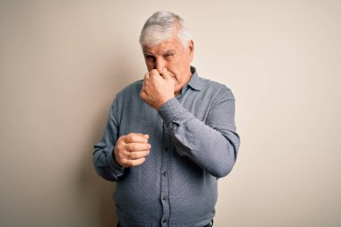 Kıdemli yakışıklı beyaz gömlekli adam izole edilmiş beyaz arka planda dikiliyor pis ve iğrenç bir koku alıyor, dayanılmaz bir koku, parmakları burnunda nefesini tutuyor. Kötü kokuyor.