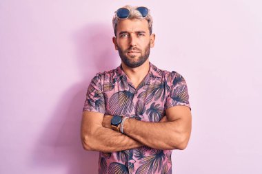 Yakışıklı sarışın, tatilde. Pembe arka planda güneş gözlüğü takıyor. Şüpheci ve gergin. Negatif kişi.
