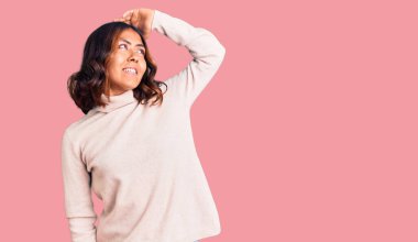 Genç, güzel, melez, balıkçı yaka kazak giyen, kendine güvenen, el hareketleriyle saçlara dokunan çekici ve modaya uygun bir kadın. 