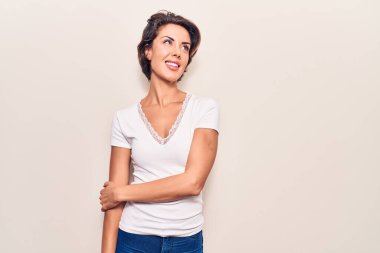 Gündelik giysiler giyen genç ve güzel bir kadın yüzünde gülümseme, doğal bir ifade ile yan yana bakıyor. Kendinden emin gülen. 