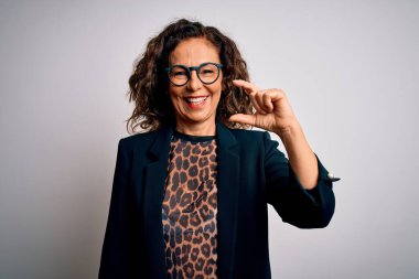 Orta yaşlı esmer iş kadını gözlüklü, gözlüklü, izole edilmiş beyaz arka planda gülümseyen, kendine güvenen, el hareketleriyle küçük boy işareti yapan, parmakları ve kamerayla bakan. Ölçü kavramı.