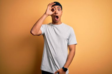 Yakışıklı Afro-Amerikan sporcusu sarı arka planda spor giysisi giyiyor. Şaşırmış yüz ifadesiyle şaşırmış, parmaklarından bakarak hareket ediyor. İnançsız ifade.