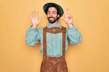 Almanya Festivali için geleneksel Alman Ekim Festivali kıyafeti giyen yakışıklı genç adam sekiz numarayı gösterip işaret ederken kendinden emin ve mutlu bir şekilde gülümsüyor..