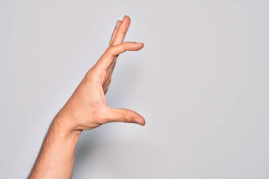 İzole edilmiş beyaz arka plan üzerinde parmaklarını gösteren beyaz bir adamın eli. Görünmez bir şeyi alıp, parmaklarıyla uzayı gösteren bir nesneyi tutuyor.