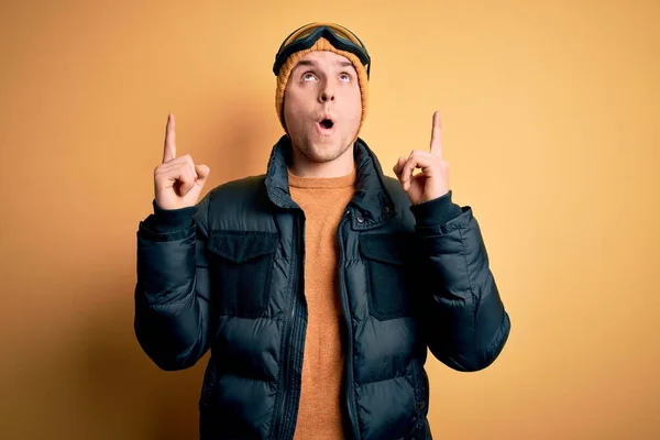겨울에는 모자를 코트를 안경을 스키를 스키를 사람이 올려다보고 손가락으로 가리키며 — 스톡 사진