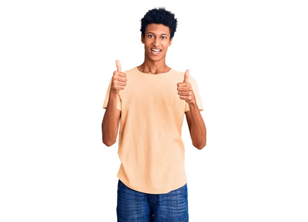 カジュアルな服を着ている若いアフリカ系アメリカ人の男性は 手で積極的なジェスチャーを行い 親指を笑顔と幸せ 陽気な表情と勝者のジェスチャー — ストック写真