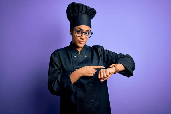 年轻的非洲女厨师 身穿炊具制服 头戴紫色背景的帽子 忙着看时间 心烦意乱 对最后期限的延误感到愤怒 — 图库照片