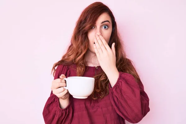 Jovem Bela Mulher Segurando Café Cobrindo Boca Com Mão Chocado — Fotografia de Stock