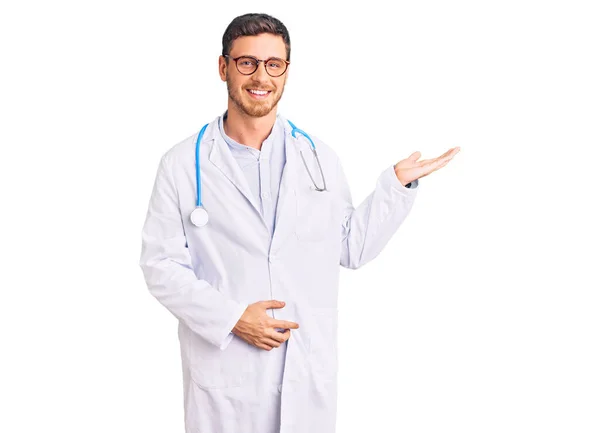 Joven Guapo Con Oso Vistiendo Uniforme Médico Sonriente Alegre Presentando —  Fotos de Stock