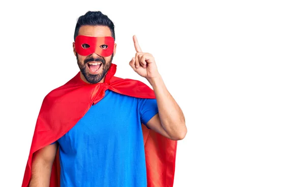 成功したアイデアで指を指す超ヒーローの衣装を着た若いヒスパニック系の男 興奮して幸せよ 第1位 — ストック写真