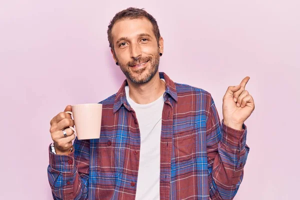 Jonge Knappe Man Houdt Koffie Glimlachend Gelukkig Wijzend Met Hand — Stockfoto