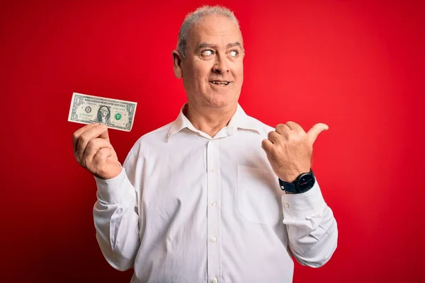 Człowiek Średnim Wieku Trzymający Banknot Dolarowy Nad Odizolowanym Czerwonym Tłem — Zdjęcie stockowe