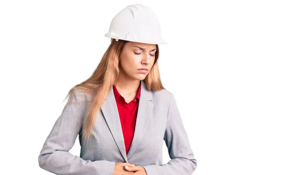 漂亮的年轻女子戴着建筑师的硬礼帽 双手放在肚子上 因为消化不良 病痛难忍 疼痛的概念 — 图库照片