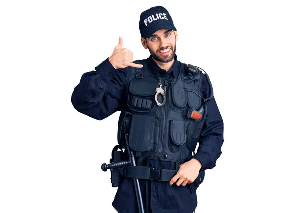 警察の制服を着た髭を生やした若いハンサムな男が電話で話すような手や指で電話のジェスチャーをして笑っている コミュニケーションの概念 — ストック写真