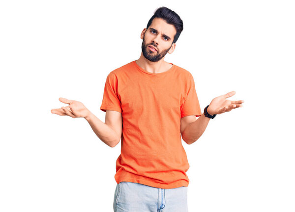 Young handsome man with beard wearing casual t-shirt clueless and confused with open arms, no idea concept. 