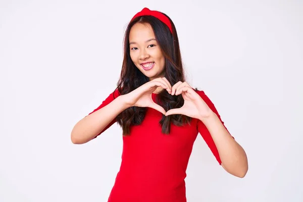 年轻美丽的中国女孩穿着休闲装 带着爱意微笑 用手做着心形符号 浪漫的概念 — 图库照片