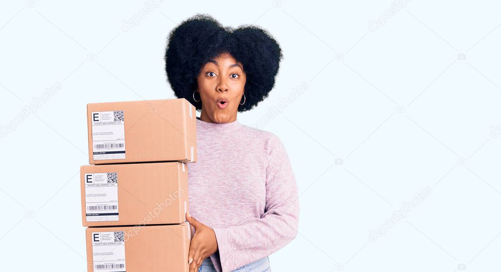 Young african american girl holding delivery package scared and amazed with open mouth for surprise, disbelief face 