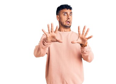 Günlük giysiler giyen genç İspanyol adam korku ifadesinden korkuyor ve dehşete düşüyor. El hareketlerini durdur, şok içinde bağır. panik konsepti. 