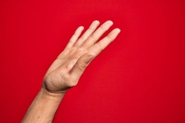 İzole edilmiş kırmızı arka plan üzerinde parmaklarını gösteren beyaz bir genç adam. Avuç içi açık bir şekilde yardım ve desteğe uzanıyor.
