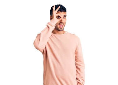 Gündelik kıyafetler giyen genç İspanyol adam el hareketleriyle gülümsüyor ve mutlu yüzüyle parmaklarından bakıyor.. 