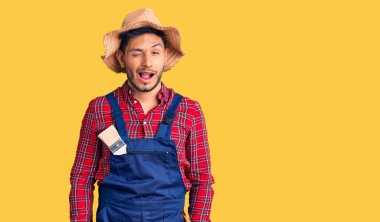 Yakışıklı Latin Amerikalı genç adam, tamirci üniforması giyiyor kameraya seksi bir ifadeyle bakıyor, neşeli ve mutlu bir yüzle.. 