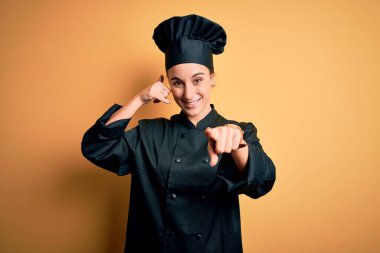 Aşçı üniforması giyen, sarı arka planda duran, gülümseyen, telefonda konuşan ve seni işaret eden genç, güzel bir şef kadın. Ara beni..