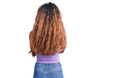 Gündelik giysiler giymiş, kollarını kavuşturup arkasını çeviren İspanyol dövmeli genç kadın. 