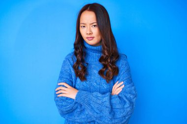 Kış süveteri giyen genç, güzel bir Çinli kız kuşkucu ve gergin. Yüzünde çapraz kollarla onaylamayan bir ifade var. negatif kişi. 