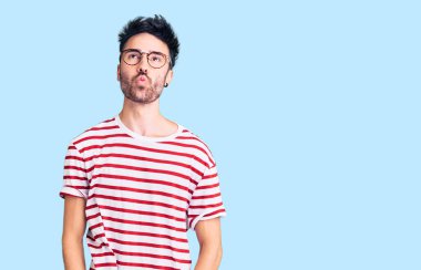 Gündelik kıyafetler giyen genç İspanyol adam dudaklarıyla balık suratı yapıyor, çılgınca ve komik bir jest. Komik ifade. 