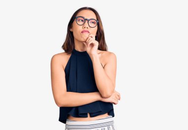 Genç, güzel Çinli bir kız, günlük kıyafetler ve gözlük takıyor ciddi bir yüz, eli çenesinde soruyu düşünüyor, kafa karıştırıcı bir fikir. 