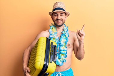 Mayo giyen genç ve kel bir adam ve Hawai leyleğinin kamara çantasını tutarken mutlu bir şekilde gülümsüyor. 