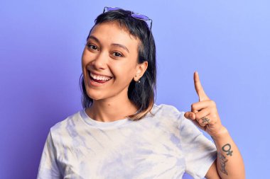 Gündelik giysiler giymiş genç bir kadın başarılı bir fikirle işaret ediyor. Heyecanlı ve mutlu. Bir numara.. 