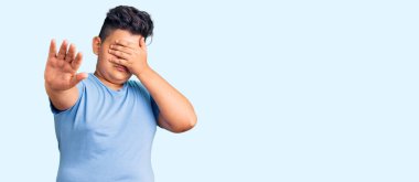 Spor kıyafetleri giyen küçük çocuk elleriyle gözlerini kapatıyor ve üzgün ve korku ifadeleriyle dur hareketi yapıyor. utangaç ve olumsuz kavram. 